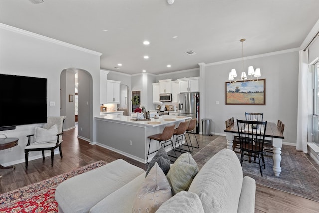 living room with dark wood-type flooring, a notable chandelier, and ornamental molding