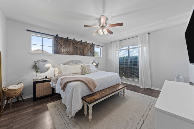 bedroom featuring ceiling fan, a barn door, dark wood-type flooring, and multiple windows