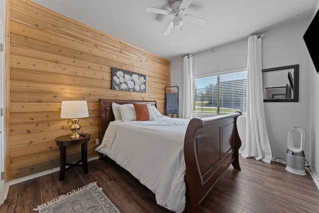 bedroom featuring ceiling fan, dark wood-type flooring, and wood walls