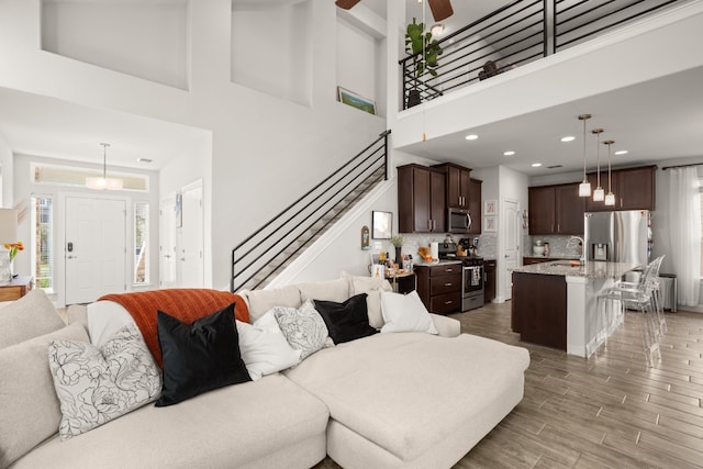 living room featuring wood-type flooring, a towering ceiling, and a healthy amount of sunlight