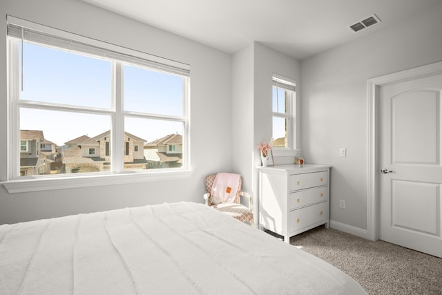 bedroom with baseboards, a residential view, visible vents, and light colored carpet