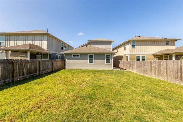 back of property with a fenced backyard and a yard