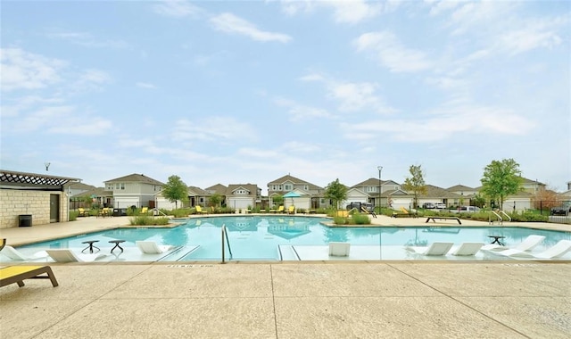 pool with a patio area, fence, and a residential view