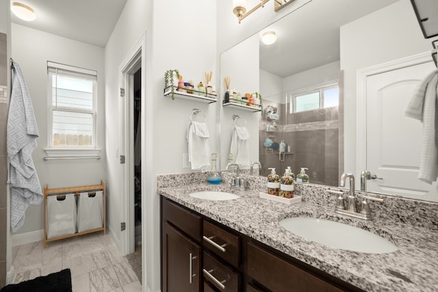 bathroom with double vanity, marble finish floor, a shower stall, and a sink