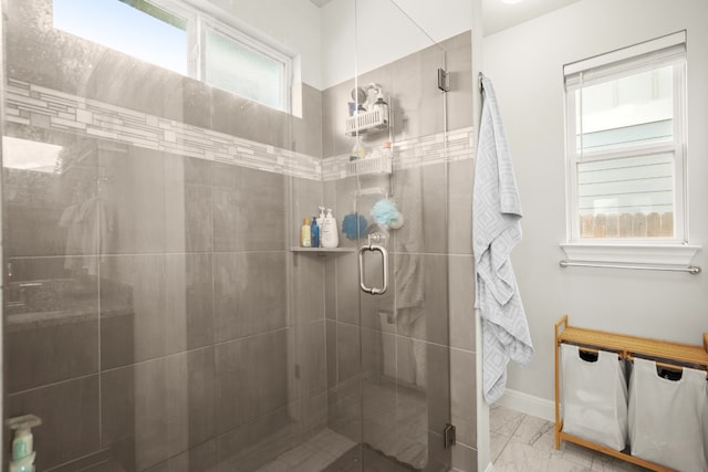 full bath with marble finish floor, a stall shower, and baseboards