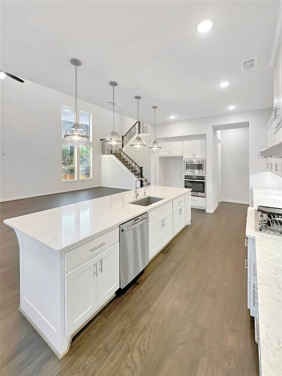 kitchen with stainless steel appliances, dark wood-style flooring, a sink, visible vents, and light countertops