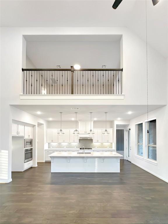 kitchen featuring pendant lighting, decorative backsplash, white cabinetry, and stainless steel appliances