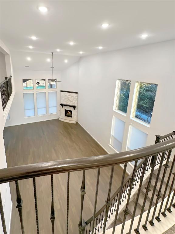 stairs with wood-type flooring and a stone fireplace