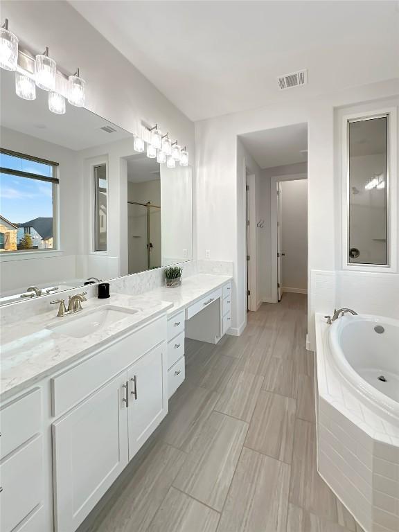 bathroom featuring tiled tub and vanity