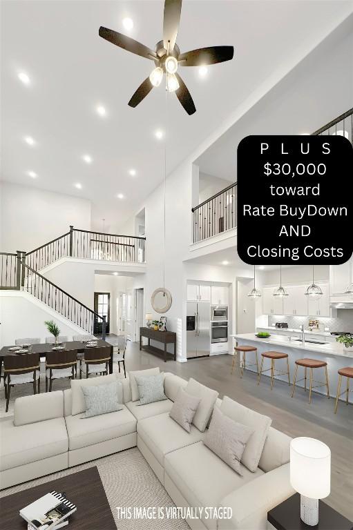 living room featuring ceiling fan and a high ceiling