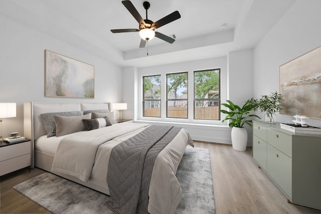 347 Five Mile Creek Way, Kyle, TX 78640 - bedroom with a raised ceiling, light wood-style flooring, and a ceiling fan