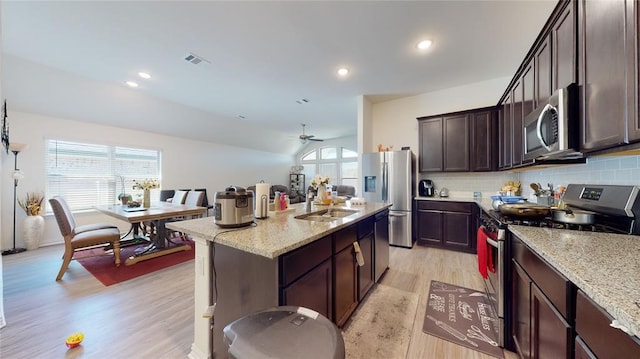 kitchen featuring appliances with stainless steel finishes, an island with sink, light stone countertops, and sink