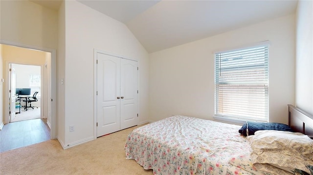 bedroom with light colored carpet, a closet, and vaulted ceiling