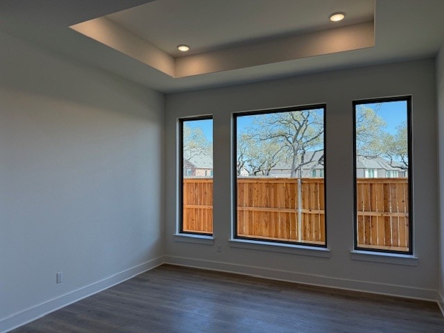 unfurnished room with a raised ceiling, baseboards, dark wood-style floors, and recessed lighting