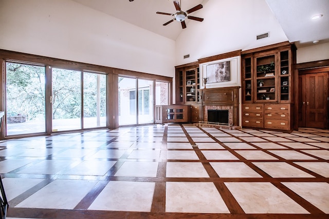 unfurnished living room with high vaulted ceiling, ceiling fan, a wealth of natural light, and a brick fireplace