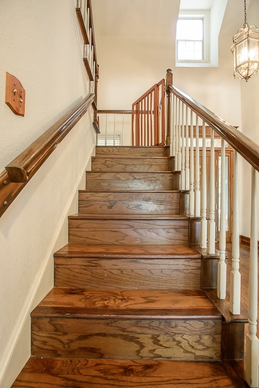 stairs featuring hardwood / wood-style floors and a notable chandelier