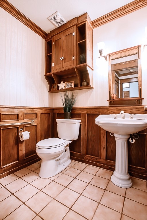 bathroom with tile patterned floors, toilet, crown molding, and sink