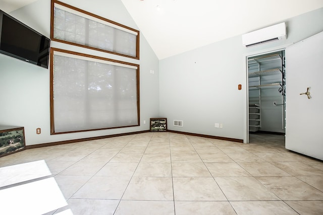 spare room featuring light tile patterned flooring, an AC wall unit, and high vaulted ceiling