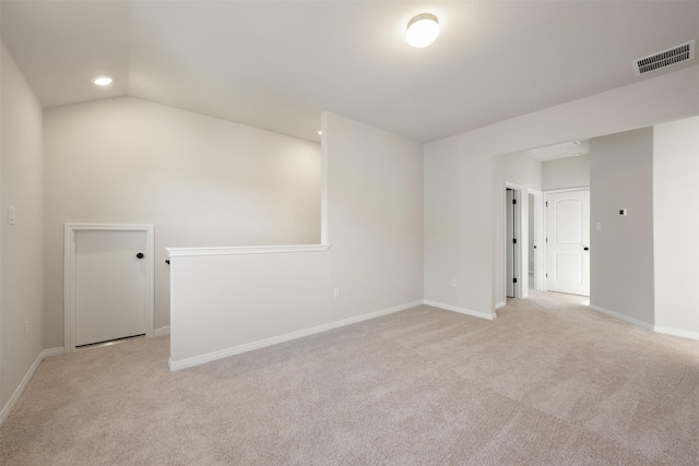 spare room with light colored carpet and vaulted ceiling