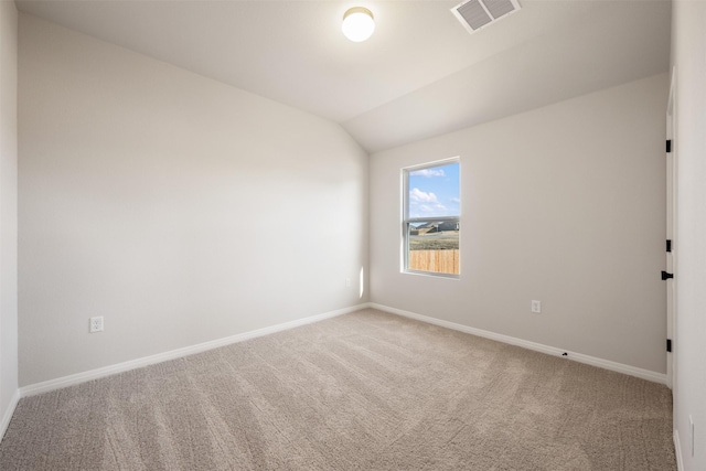 carpeted spare room featuring vaulted ceiling