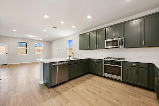 kitchen with sink, light hardwood / wood-style flooring, stainless steel appliances, and green cabinets