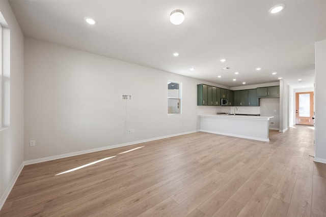 unfurnished living room with sink and light wood-type flooring