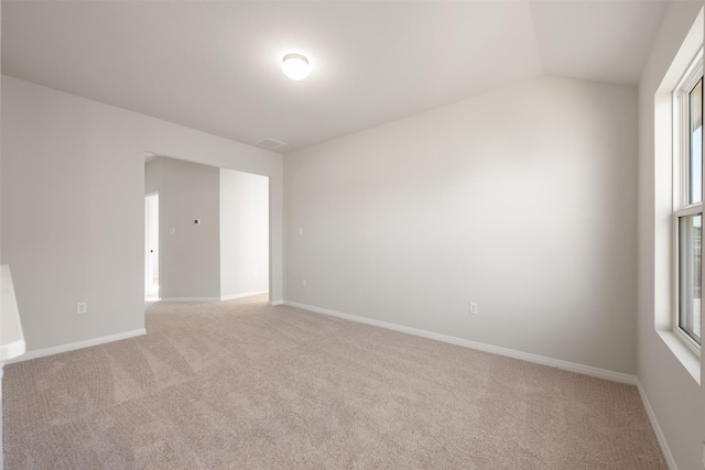 carpeted spare room featuring vaulted ceiling