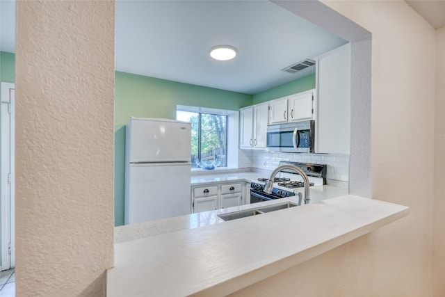 kitchen with backsplash, white cabinetry, sink, and white appliances