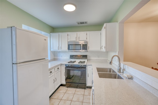 kitchen with white cabinetry, stove, white fridge, and sink