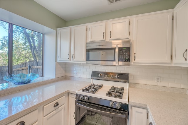 kitchen featuring range, tasteful backsplash, and white cabinetry