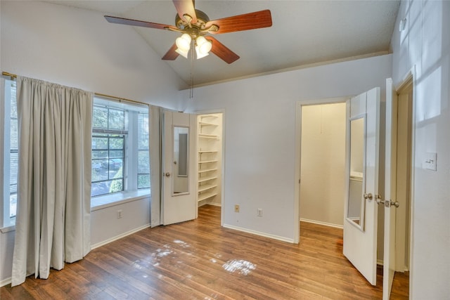 unfurnished bedroom featuring ceiling fan, a spacious closet, light hardwood / wood-style flooring, and vaulted ceiling