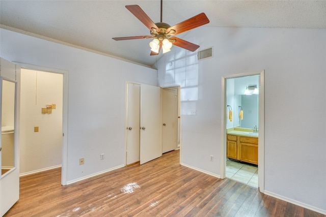 unfurnished bedroom featuring high vaulted ceiling, sink, light hardwood / wood-style flooring, ensuite bath, and ceiling fan