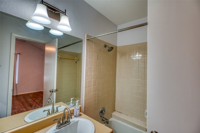 bathroom featuring hardwood / wood-style floors, tiled shower / bath combo, and sink