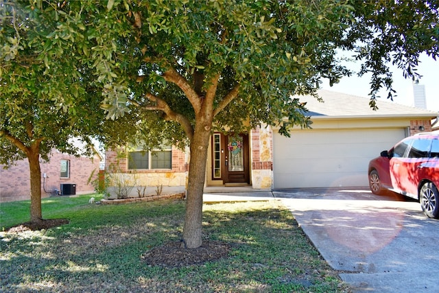 view of property hidden behind natural elements with central air condition unit, a front yard, and a garage