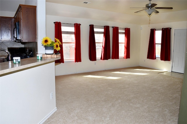 interior space with light colored carpet, ceiling fan, and a wealth of natural light