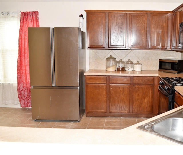 kitchen featuring appliances with stainless steel finishes, decorative backsplash, sink, and light tile patterned floors