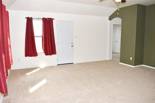 empty room featuring ceiling fan, vaulted ceiling, and light carpet