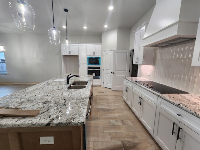 kitchen with a spacious island, sink, premium range hood, white cabinetry, and oven