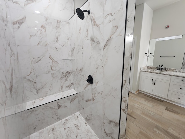 bathroom featuring tiled shower, hardwood / wood-style flooring, and vanity