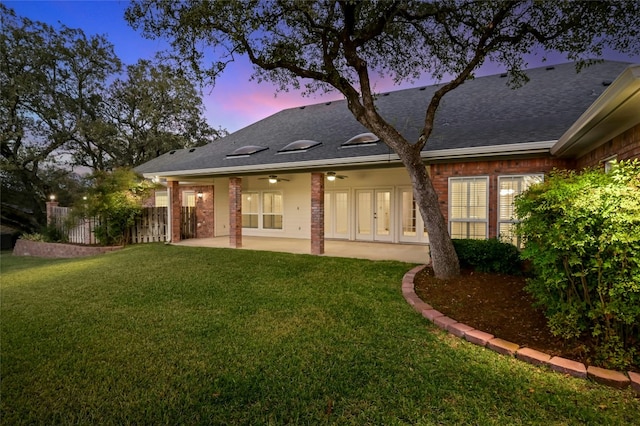 back house at dusk with a yard, ceiling fan, and a patio area