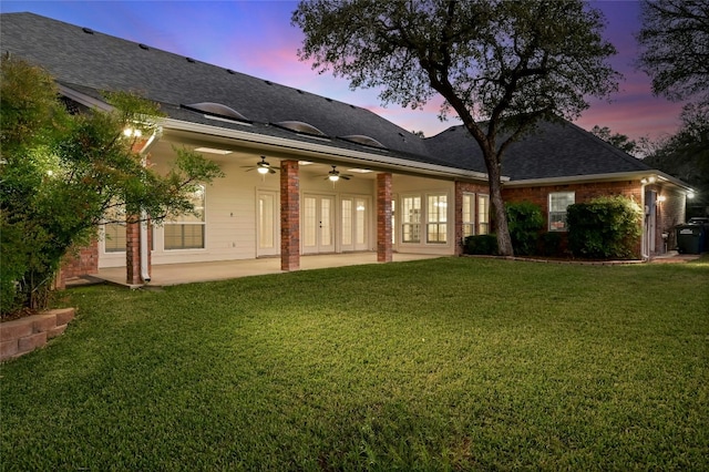 back house at dusk with a patio area, ceiling fan, and a yard