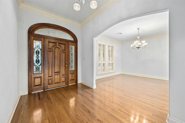 entryway with crown molding, a notable chandelier, and hardwood / wood-style flooring