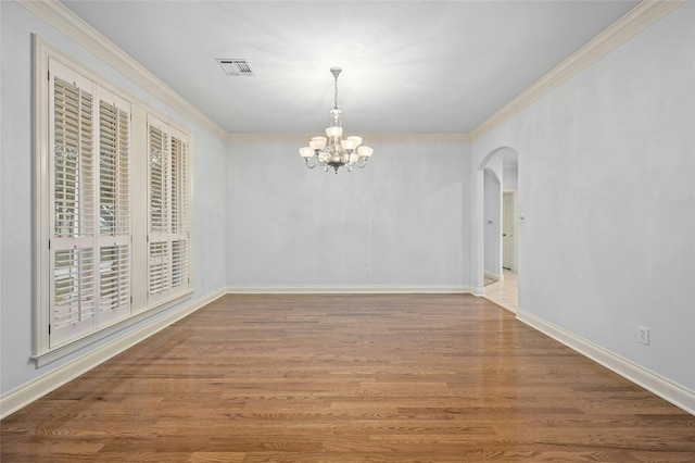 unfurnished dining area with wood-type flooring, crown molding, and an inviting chandelier