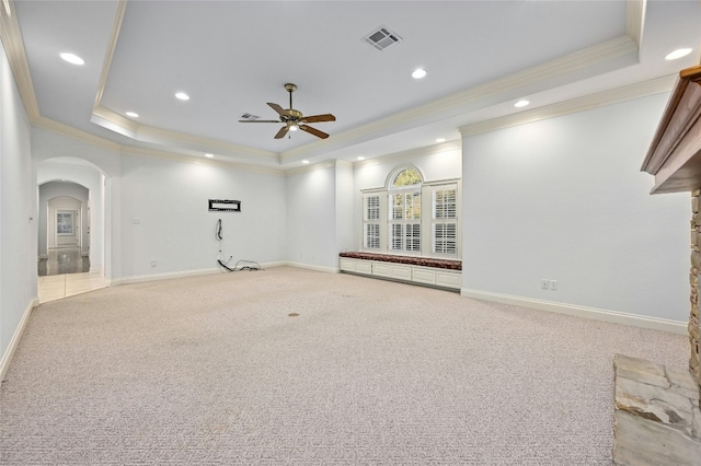 unfurnished living room featuring a raised ceiling, light carpet, crown molding, and ceiling fan