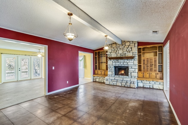 unfurnished living room featuring a textured ceiling, ceiling fan, lofted ceiling with beams, dark tile patterned flooring, and a fireplace