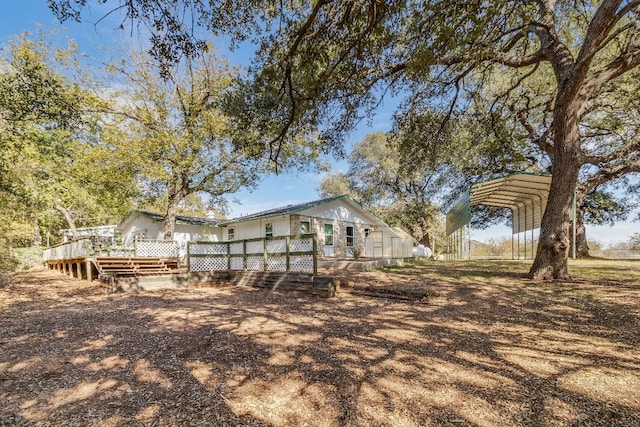 rear view of property with a deck and a carport