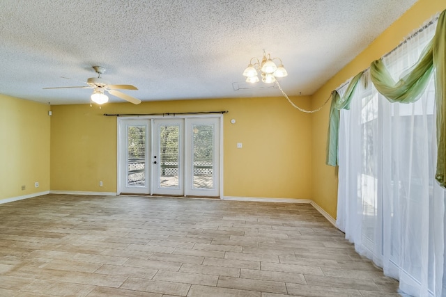 empty room with ceiling fan with notable chandelier, light hardwood / wood-style floors, a textured ceiling, and french doors