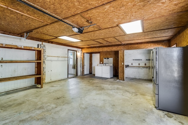 garage featuring a garage door opener, independent washer and dryer, and stainless steel refrigerator