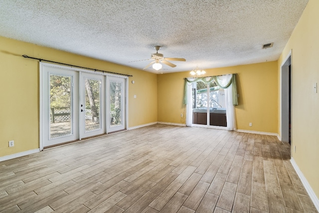 unfurnished room with ceiling fan with notable chandelier, a textured ceiling, light wood-type flooring, and plenty of natural light