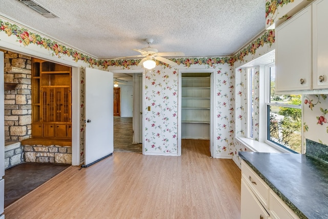 unfurnished dining area with a textured ceiling, light hardwood / wood-style floors, and ceiling fan